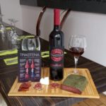 Bouteille de vin de framboises bio bulgares présenté sur planche avec noix de porc aux herbes.