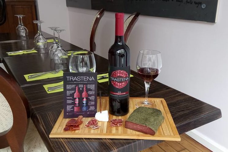 Bouteille de vin de framboises bio bulgares présenté sur planche avec noix de porc aux herbes.
